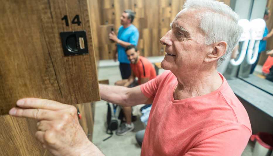Señor mayor abriendo un casillero en el baño de un gimnasio.