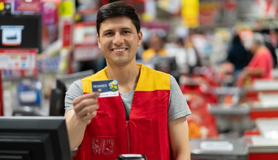 Cajero de una tienda de mejoras para el hogar sosteniendo una tarjeta de membresía. Cajero de una tienda de mejoras para el hogar sosteniendo una tarjeta de membresía.