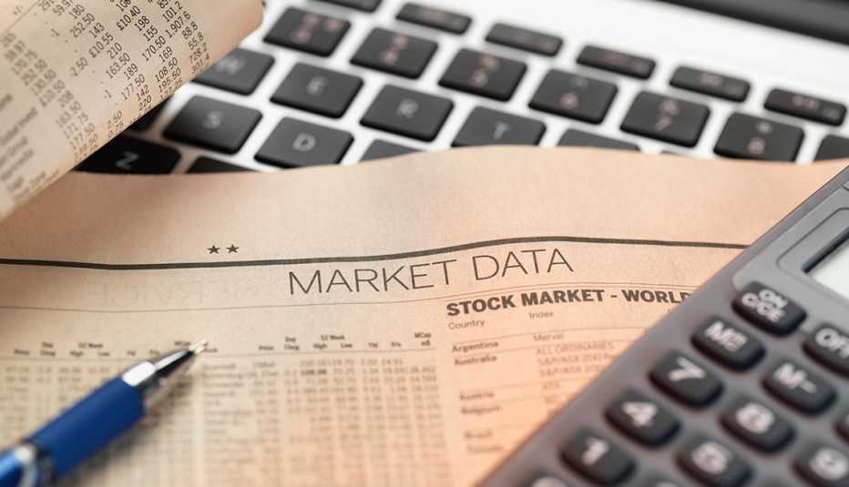 Hoja del mercado de valores sobre una computadora y una calculadora Hoja del mercado de valores sobre una computadora y una calculadora