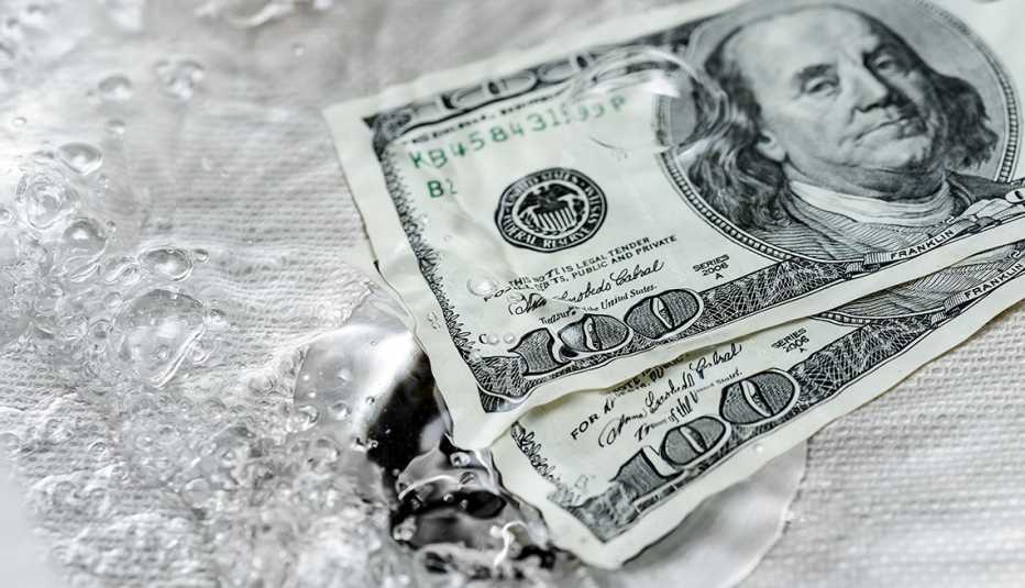 Dos billetes de 100 dólares que se van por un desagüe.