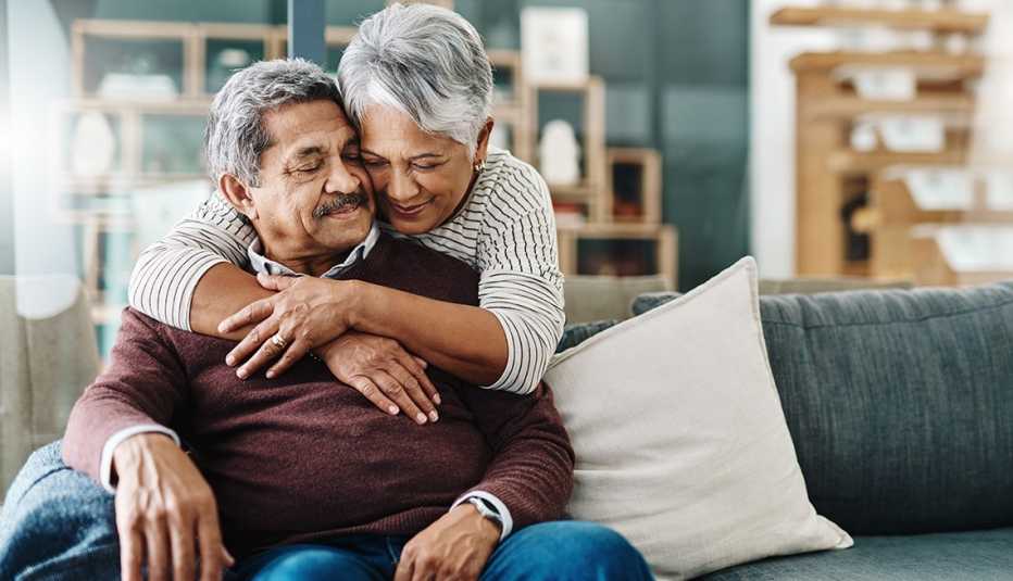 una pareja se abraza en su casa sobre un sofá