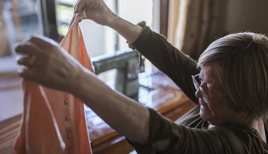 Señora mayor examinando un vestido que sostiene con sus manos estirada hacia arriba. Señora mayor examinando un vestido que sostiene con sus manos estirada hacia arriba.