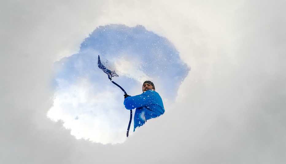 Vista desde la parte interior de un hueco en la nieve que deja ver un hombre con una pala. 