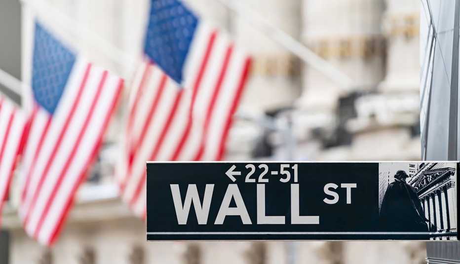 Señal de la calle Wall, en el centro financiero de Nueva York con banderas de Estados Unidos.