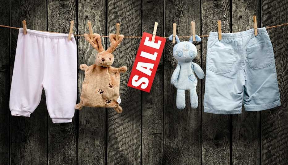 juguetes de peluche usados, pantalones para niños y un cartel de venta, colgados de clips para ropa