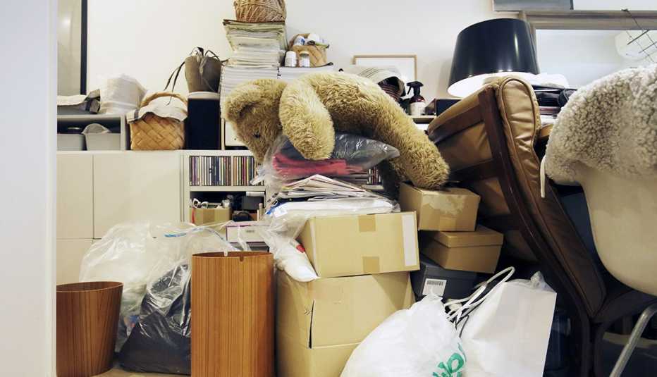 Oso de peluche, computador, cajas, y bolsas amontonadas en un cuarto.