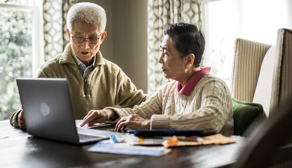 Pareja mayor revisando cuentas frente a una computadora