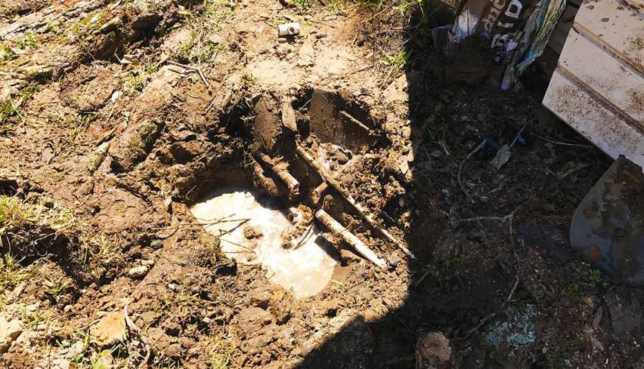 Hueco en la suelo de una propiedad que muestra una tubería de agua rota