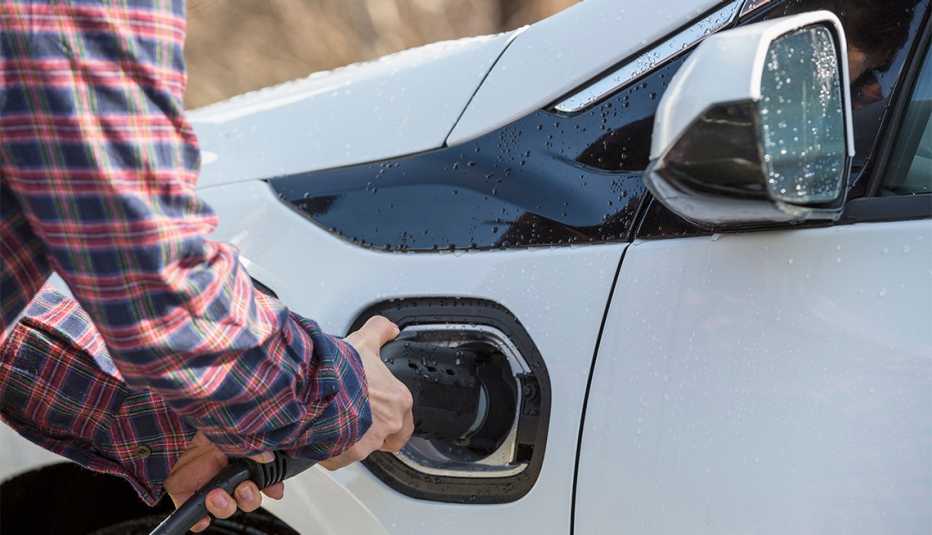 Hombre conectando un auto eléctrico a la estación de carga