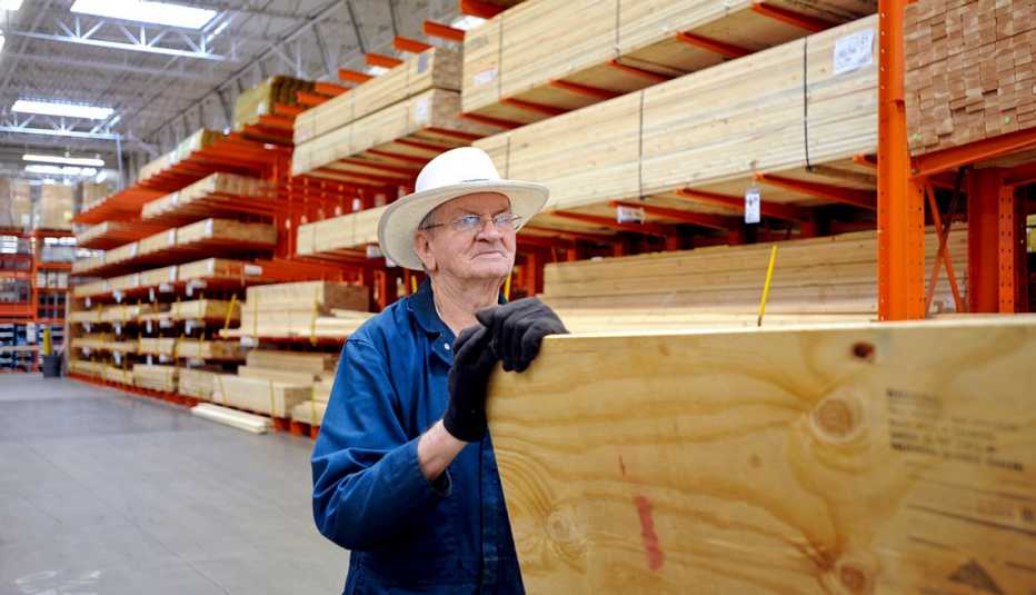 Hombre arrastrando un retablo de madera de venta en una tienda al por mayor