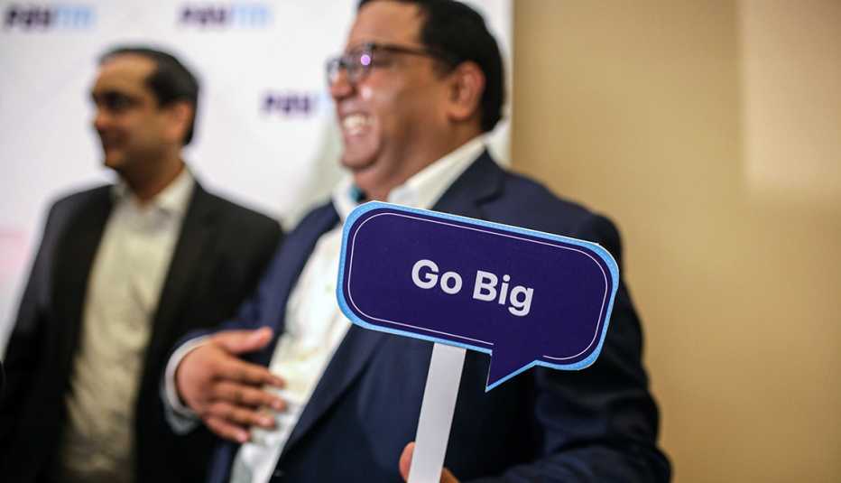 Inversionistas en una conferencia y uno de ellos sostiene un letrero que dice ve en grande Inversionistas en una conferencia y uno de ellos sostiene un letrero que dice ve en grande