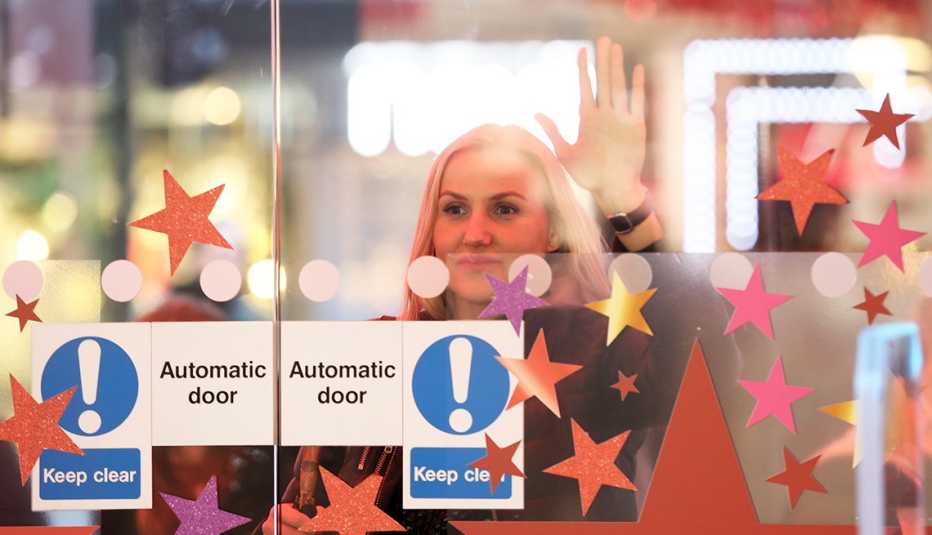 Mujer espera que abran la puerta de una tienda por departamentos