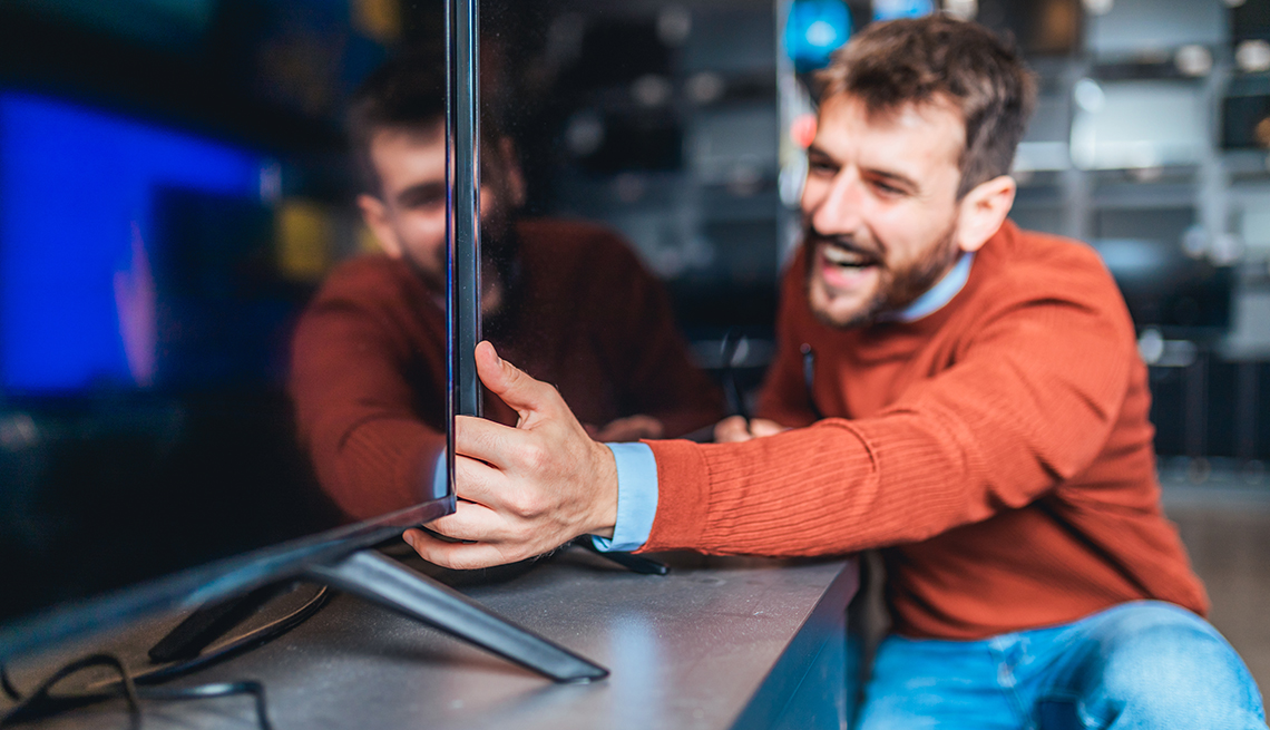 Hombre sosteniendo un televisor en una tienda de electrodomésticos
