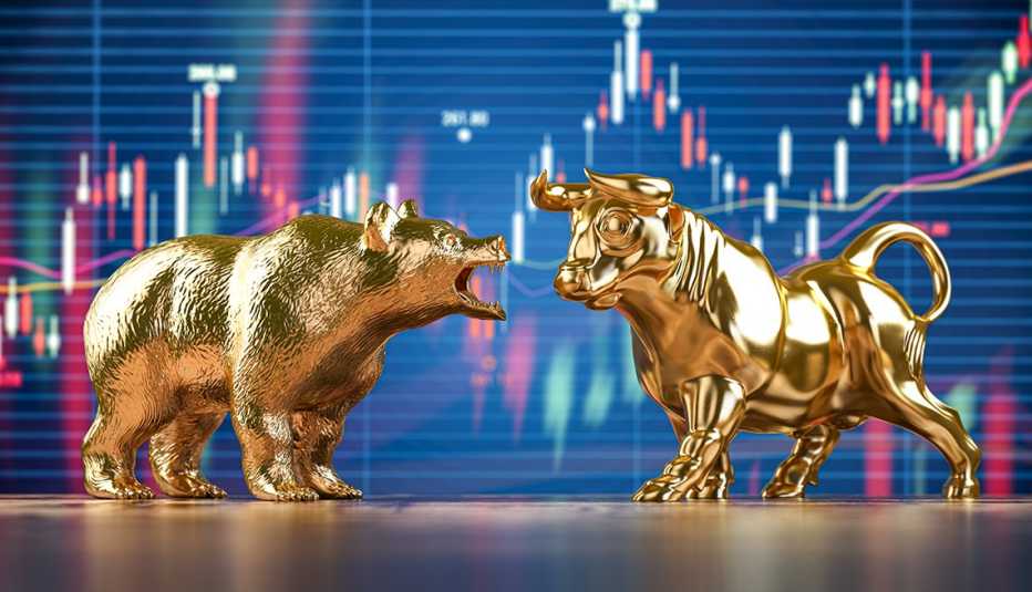 Figuras de un oso y un toro bañados en oro frente a una gráfica de la bolsa de valores Figuras de un oso y un toro bañados en oro frente a una gráfica de la bolsa de valores