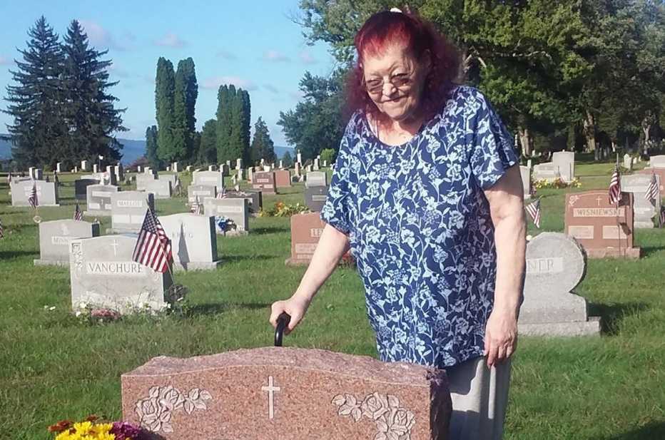 Marcelle ante la tumba de sus padres en el cementerio.