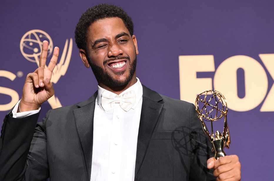 Jharrel Jerome saluda sujetando su premio Emmy.