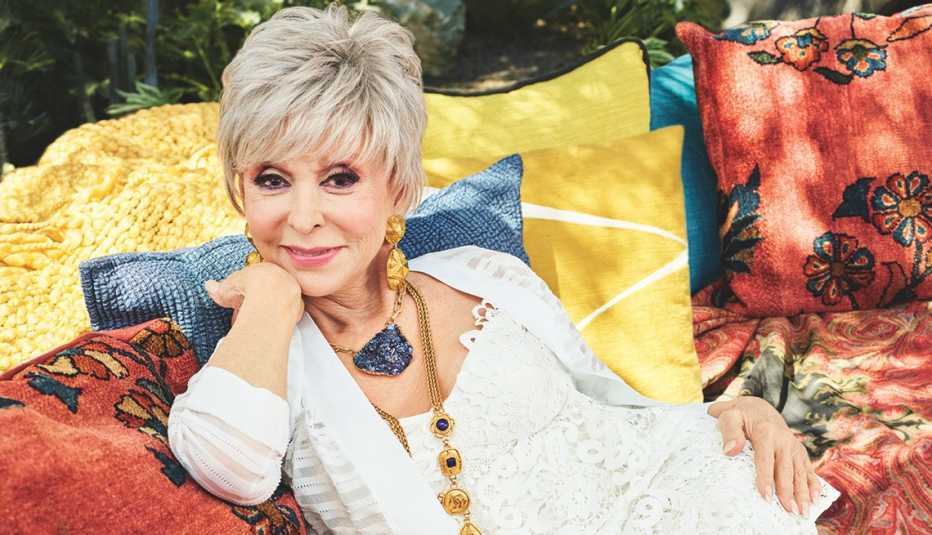 Rita Moreno sentada en un sofá al aire libre