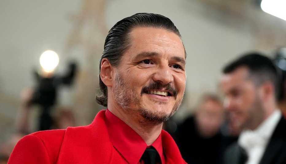 Pedro Pascal sonríe vestido de rojo.