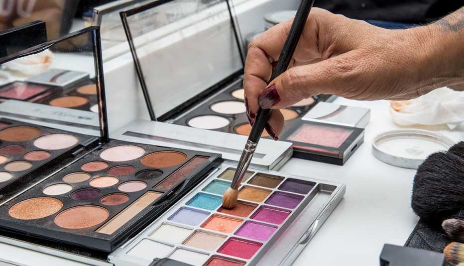 Cajas de maquillaje y una mano sosteniendo una brocha Cajas de maquillaje y una mano sosteniendo una brocha