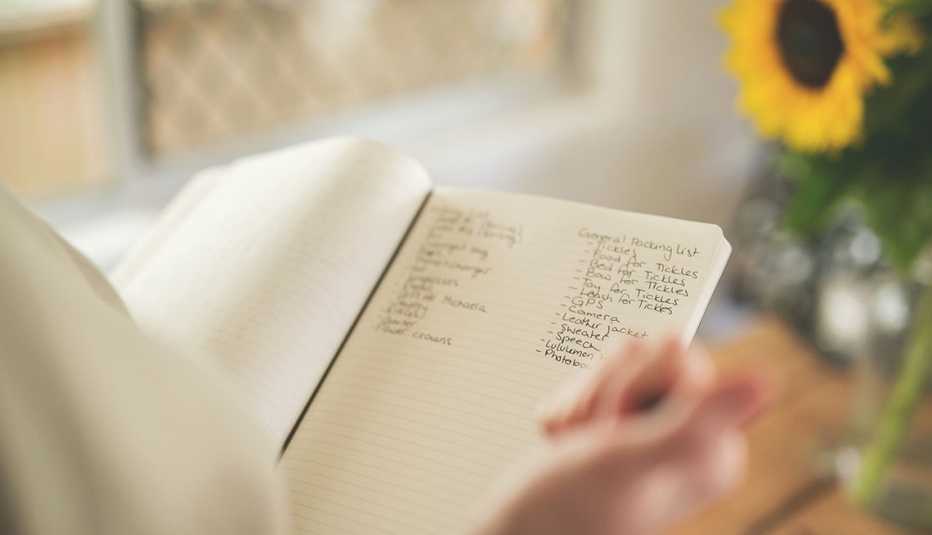 Manos sosteniendo una libreta de apuntes y haciendo cuentas en los dedos.