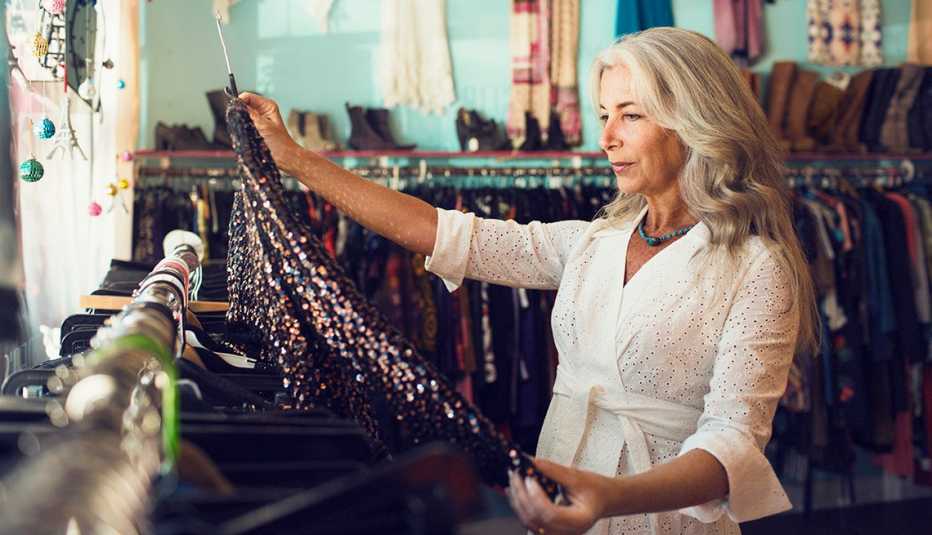 Una mujer mayor mira una blusa en una tienda de ropa.