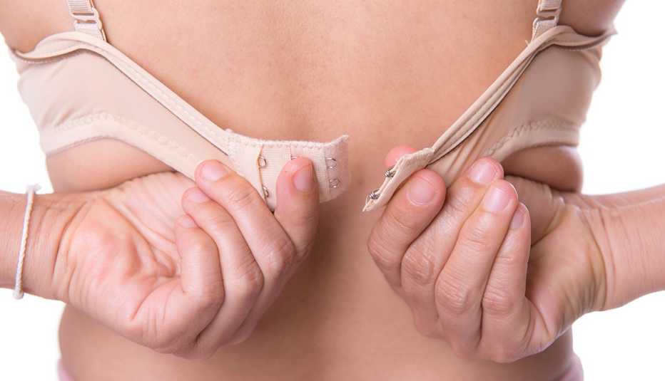 Vista trasera de una mujer mientras se abrocha el sostén.