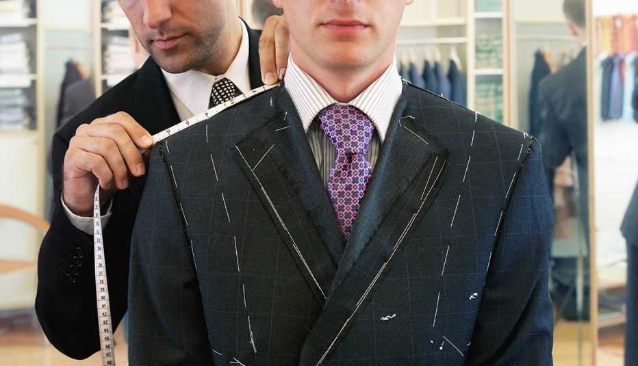 Hombre es medido por un sastre para un traje