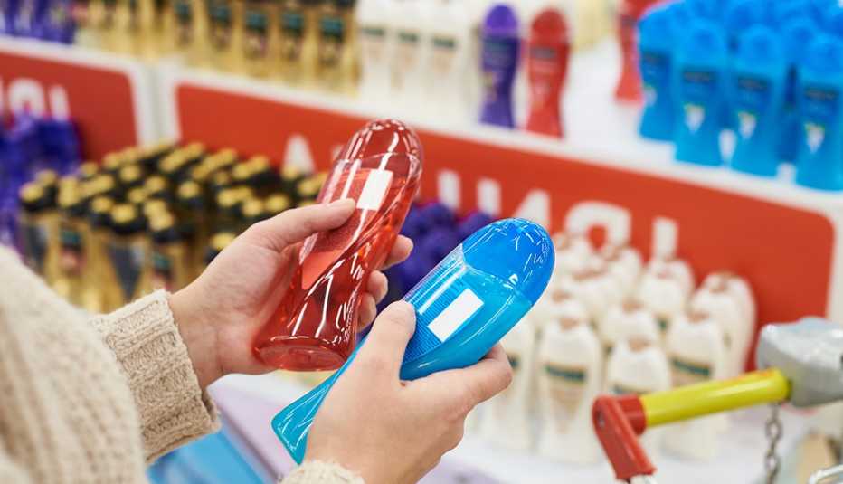 Una mujer sosteniendo dos botellas de champú dentro de una tienda.