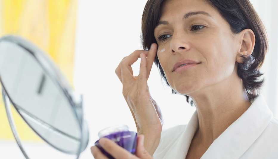 Mujer untándose crema en la cara