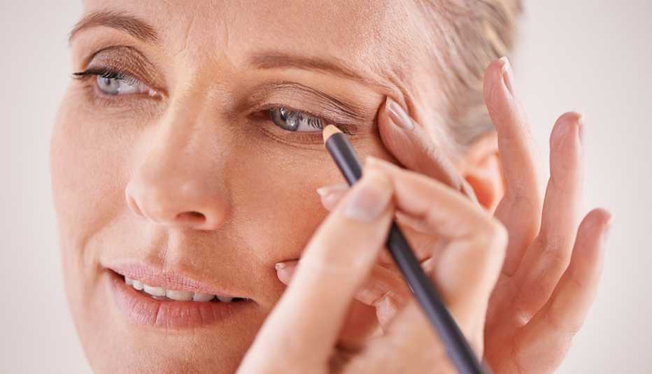 Una mujer aplicando delineador de ojos.