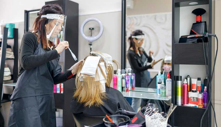 Peluquero aplicando reflejos a un cliente durante la pandemia..