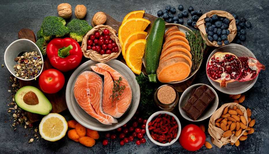 Una mesa con variedad de verduras, frutos secos, nueves y pescado.