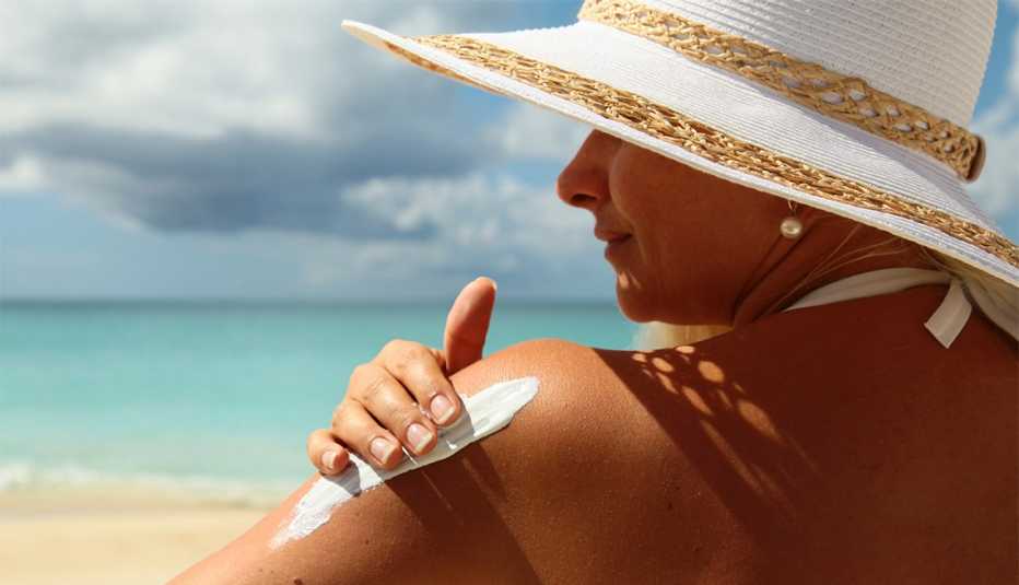 Mujer en una playa colocándose bloqueador solar