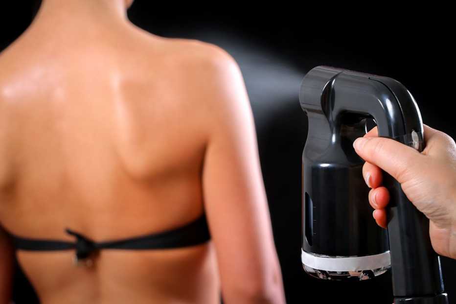 Una mujer mientras la broncean con un rociador. Una mujer mientras la broncean con un rociador.
