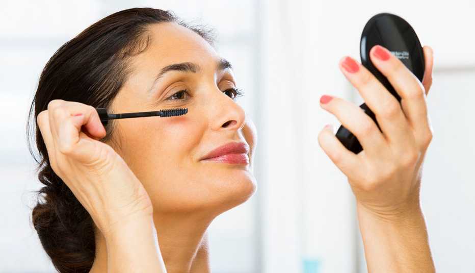 Una mujer aplicando maquillaje en sus ojos.