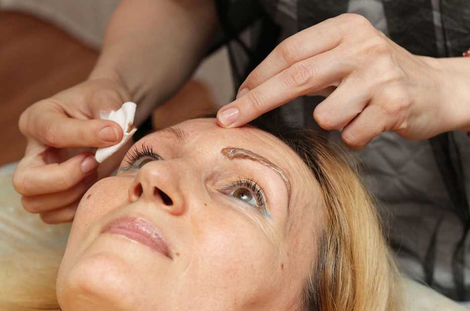 Una mujer recibiendo un tratamiendo para teñir sus cejas.