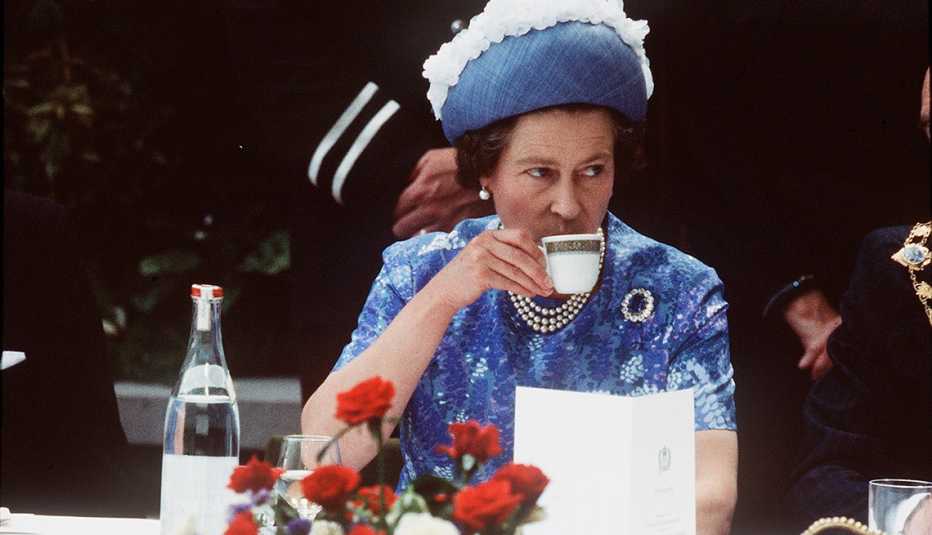La reina Isabel II bebiendo una taza de té durante una visita real de 1977 en Irlanda del Norte.