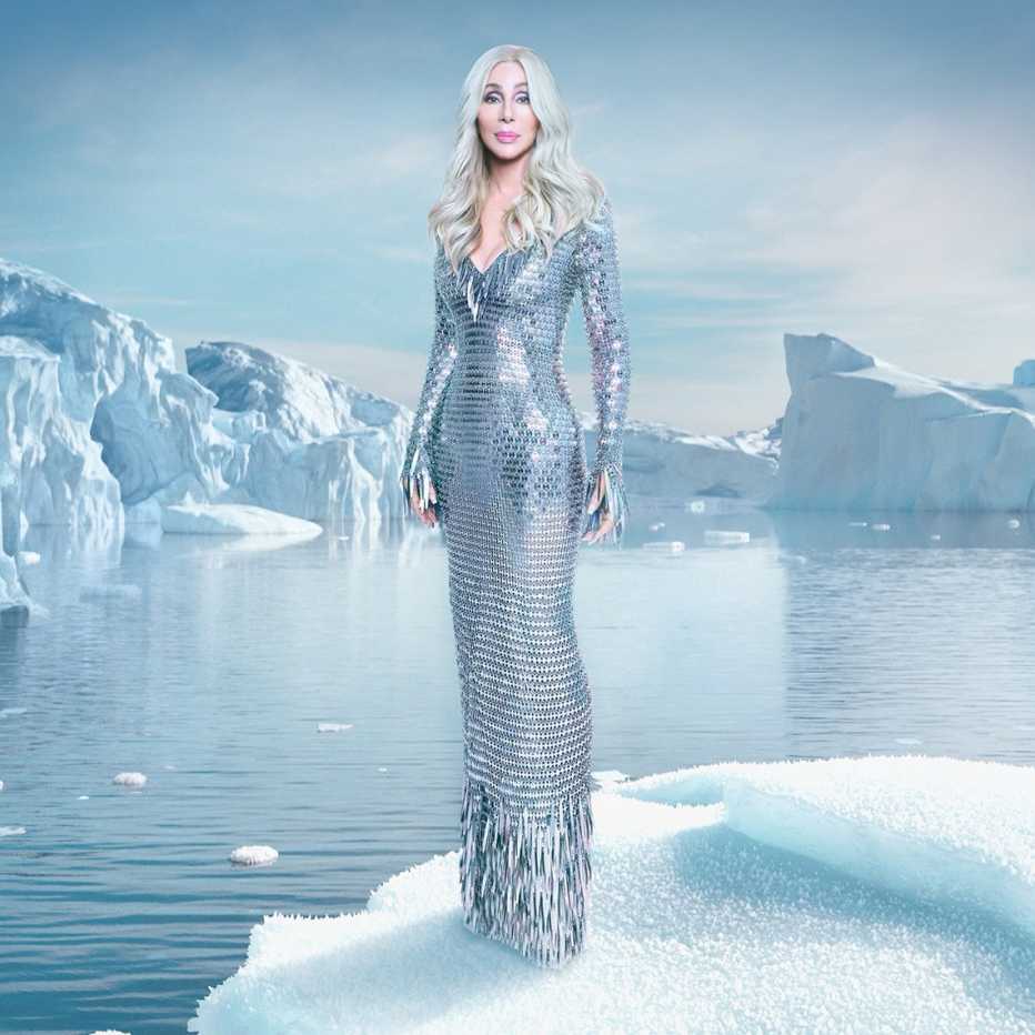 Cher con un vestido plateado posa con témpanos de hielo al fondo.