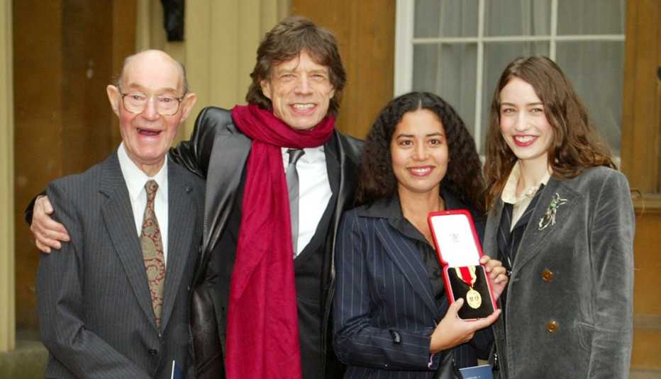 Sir Mick Jagger con su orgulloso padre, Joe, y sus hijas Elizabeth y Karis, muestran el título de caballero que Mick recibió por su contribución a la música popular durante una ceremonia que el príncipe de Gales celebró en el palacio de Buckingham el 12 de diciembre del 2003.