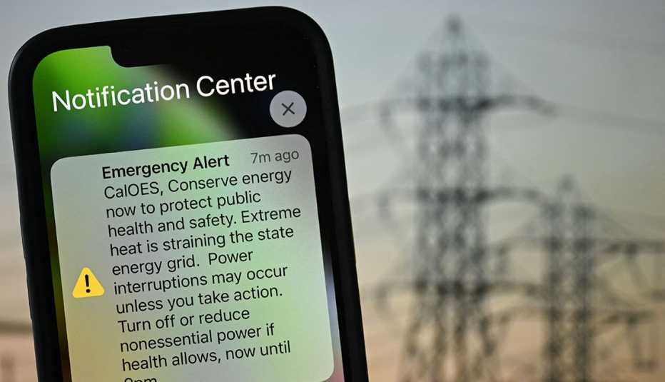 ilustración de un teléfono inteligente mostrando una alerta de emergencia con lineas eléctricas al fondo