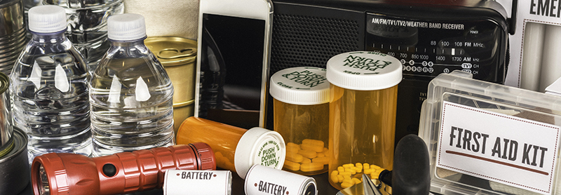supplies for a disaster prep kit including bottles water first aid kit medications batteries a transistor radio and flashlight
