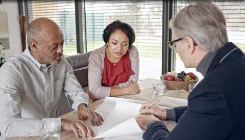 couple meets with contractor and view layouts for home renovations couple meeting with contractor in an office