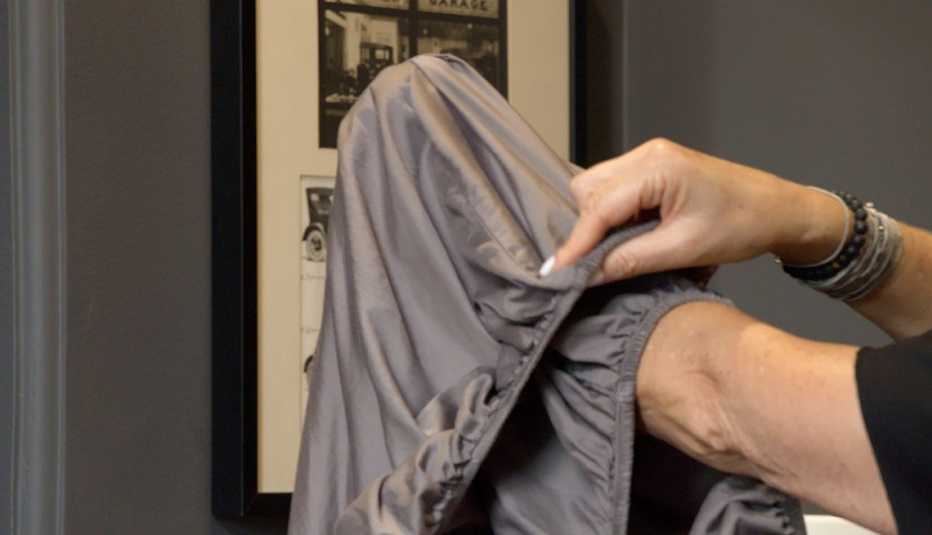 Persona dobla la sábana con una mano dentro de una de sus esquinas