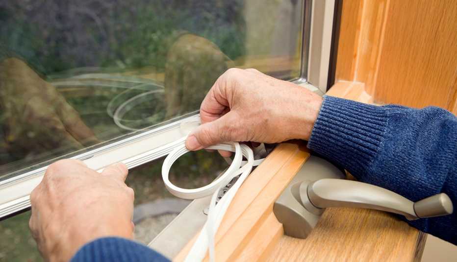Persona sella los bordes de la ventana de una casa