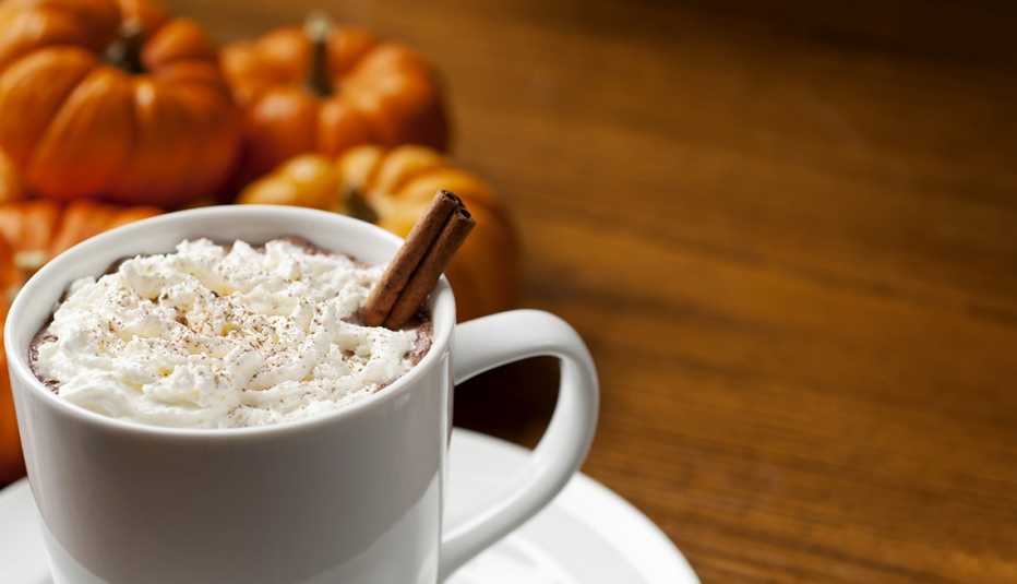 Taza de café con leche de especias de calabaza con crema batida y canela en rama