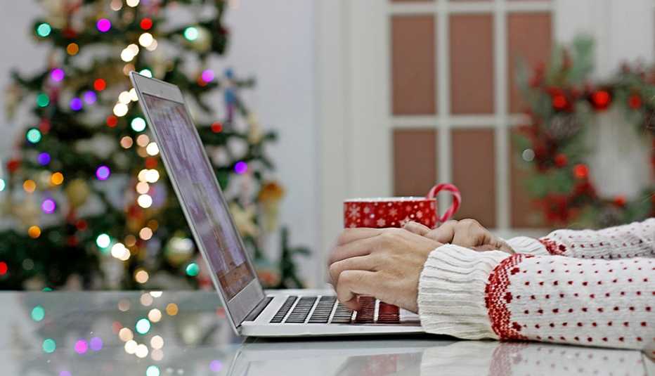Persona compra regalos de Navidad en su computadora Persona compra regalos de Navidad en su computadora
