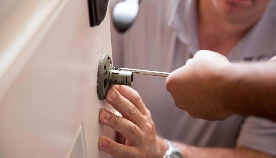 Dos personas instalan una cerradura en una puerta de madera Dos personas instalan una cerradura en una puerta de madera
