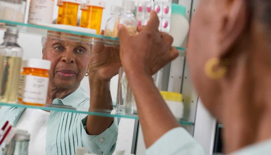 Mujer abre el gabinete de medicinas en el baño