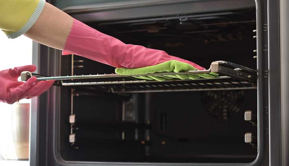 Mujer limpia el horno de su cocina