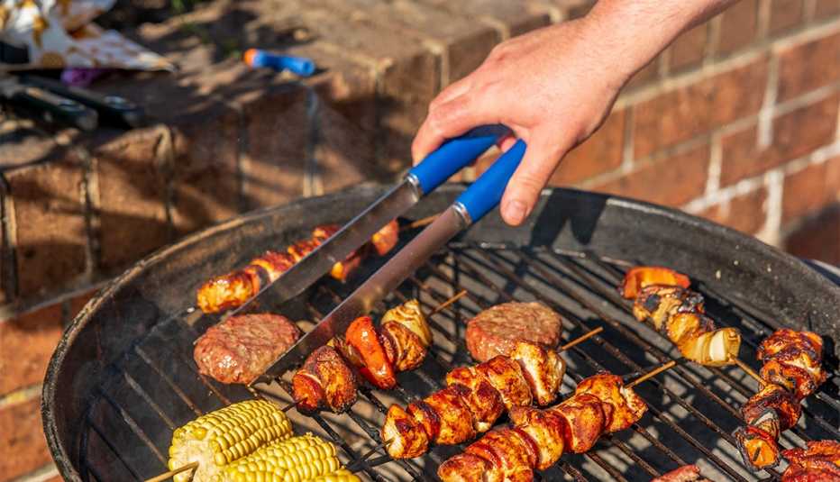 Hamburguesas, kebabs de pollo y maíz sobre una parrilla